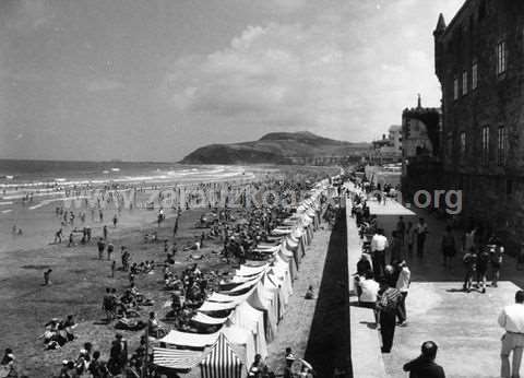 Bañistas en la playa y gente paseando en el malecón de Zarautz